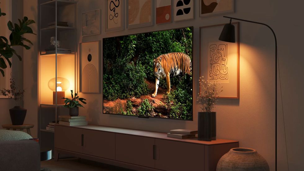 fire tv omni mini-led tv on the wall with a tiger on-screen colour-matched to the warm glow from the lamps