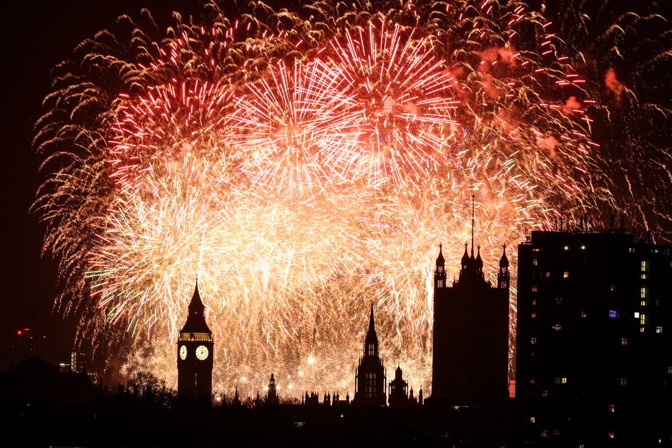 Fireworks explode in the sky around the London Eye and The Elizabeth Tower, commonly known by the name of the clock's bell, 