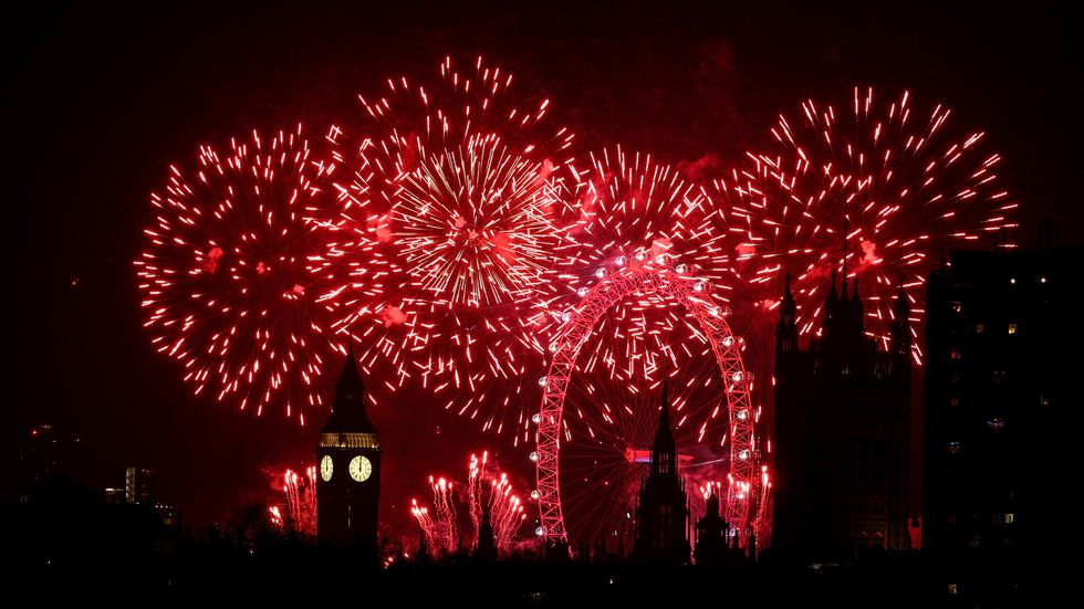 Fireworks explode in the sky around the London Eye and The Elizabeth Tower,