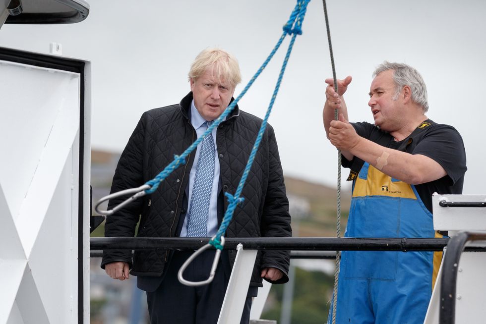 Former Prime Minister Boris Johnson talks to Ronnie Norquoy, owner of Celtic Dawn Fishing as crabs caught on the Carvela are brought in, at Stromness Harbour