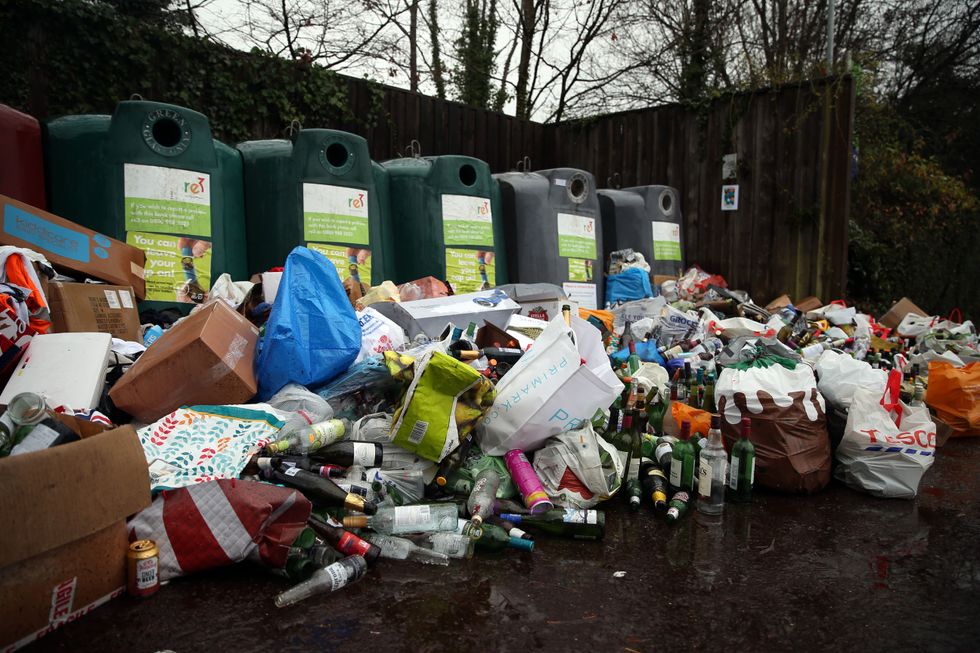 Glass bottles are left littered in front of recycling bins