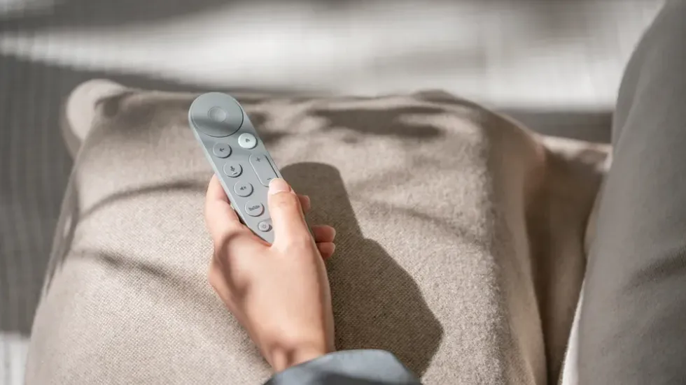 hand holds the google tv streamer remote control in hazel