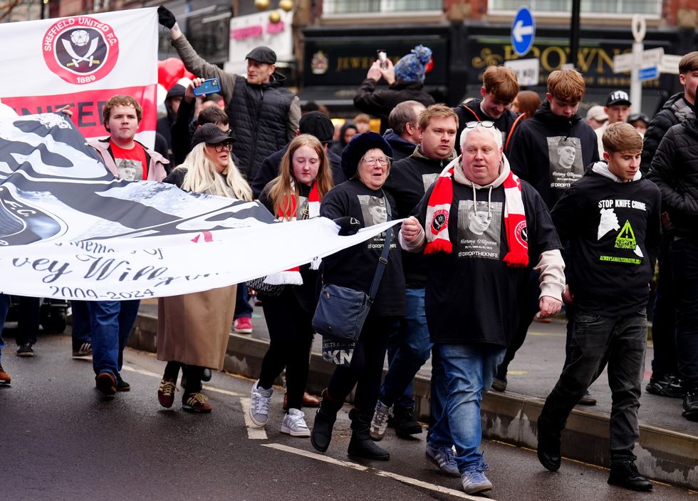 Harvey Willgoose's father Mark Willgoose holds a banner as he marches to Bramall Lane in memory of his sonu200b