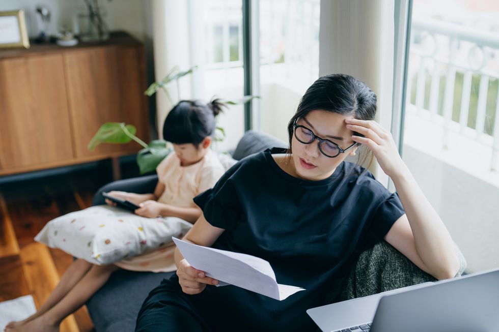 Homeowner looks at mortgage letter with child beside her