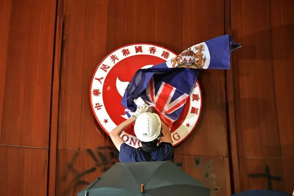 Hong Kong pro-democracy activists cover the seal of the territory with its British colonial ensign