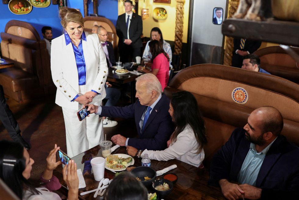 Joe Biden sits as Maritza Rodriguez, the Latino adviser for Biden's Nevada state campaign, stands at Lindo Michoacan Mexican Restaurant