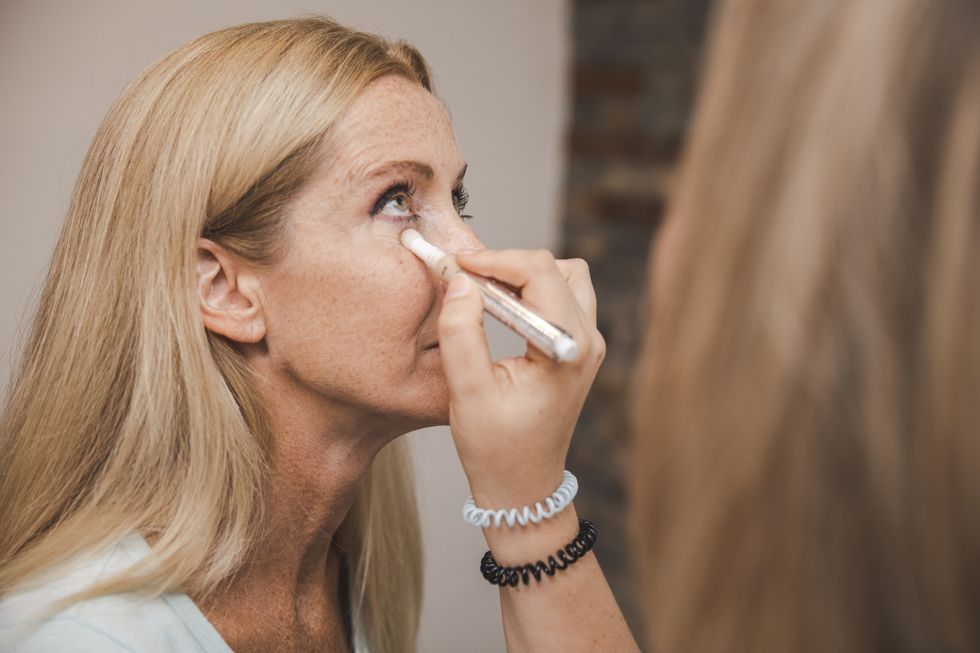 Makeup artist applying concealer to a woman's face