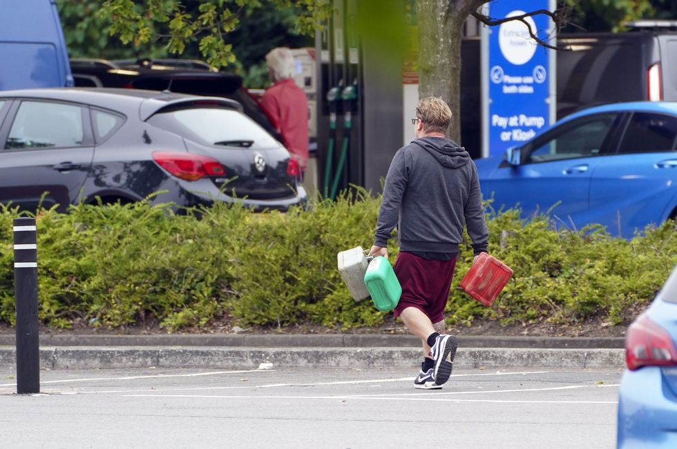 Man carrying jerrycans full of petrol away from a Tesco filling station