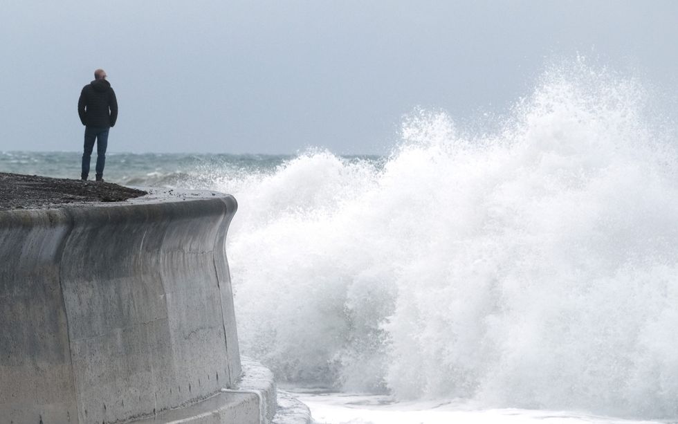 Man looks over sea wall at large waves