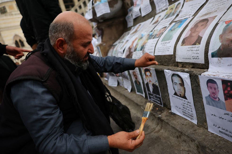 Man putting up posters of missing people in Damascus