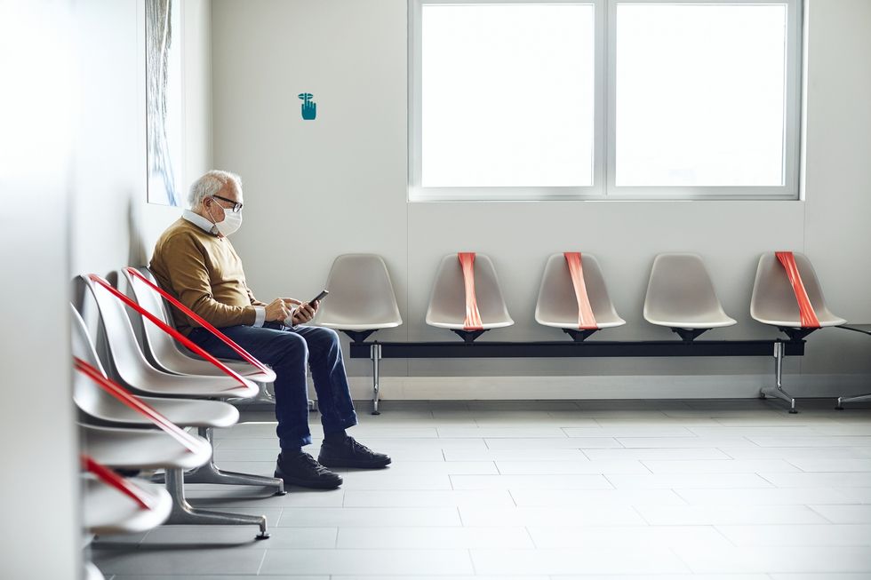 Man sits in hospital wearing a face mask