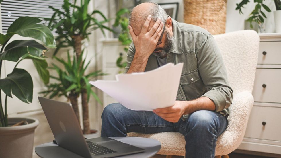 Man worried about bills sits with head in hand