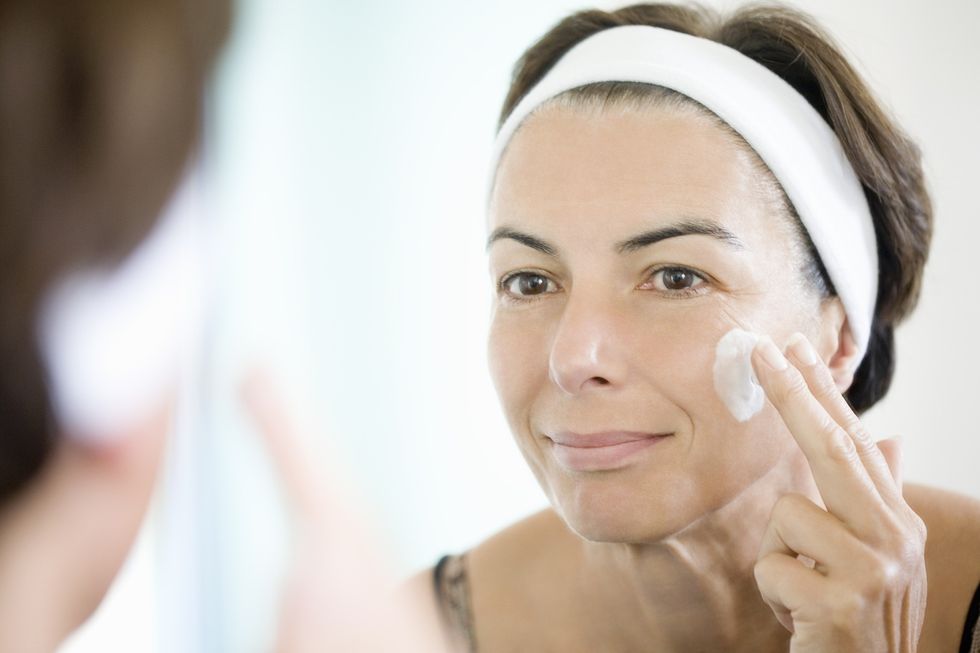 Mature woman applying skin care product to her face