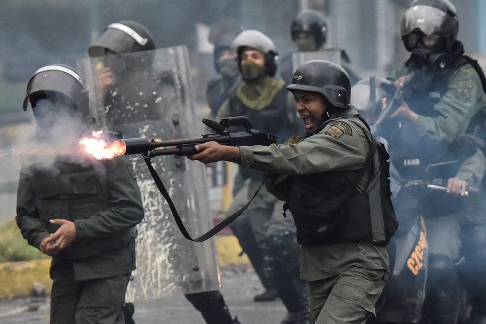 member of the national guard fires his shotgun at protesters during clashes in Caracas, Venezuela on July 28, 2017