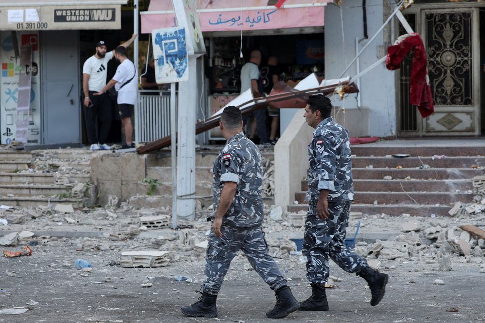 Members of the Lebanese Internal Security Forces walk past a debris-strewn street following an Israeli strike