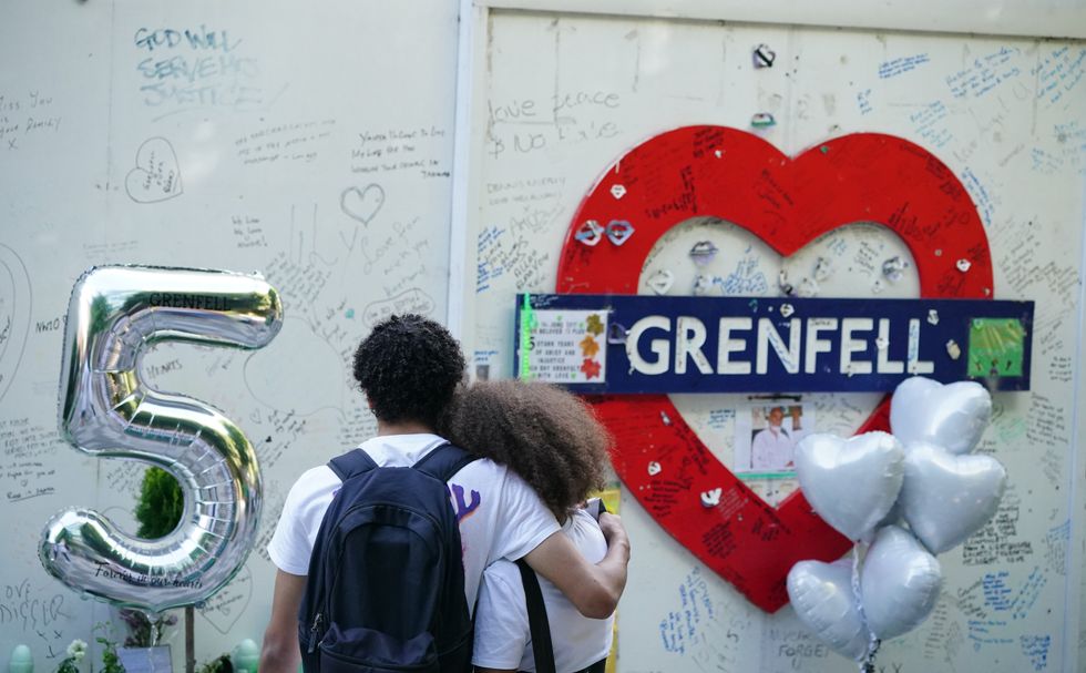 Members of the public at the memorial at the base of Grenfell Tower in London