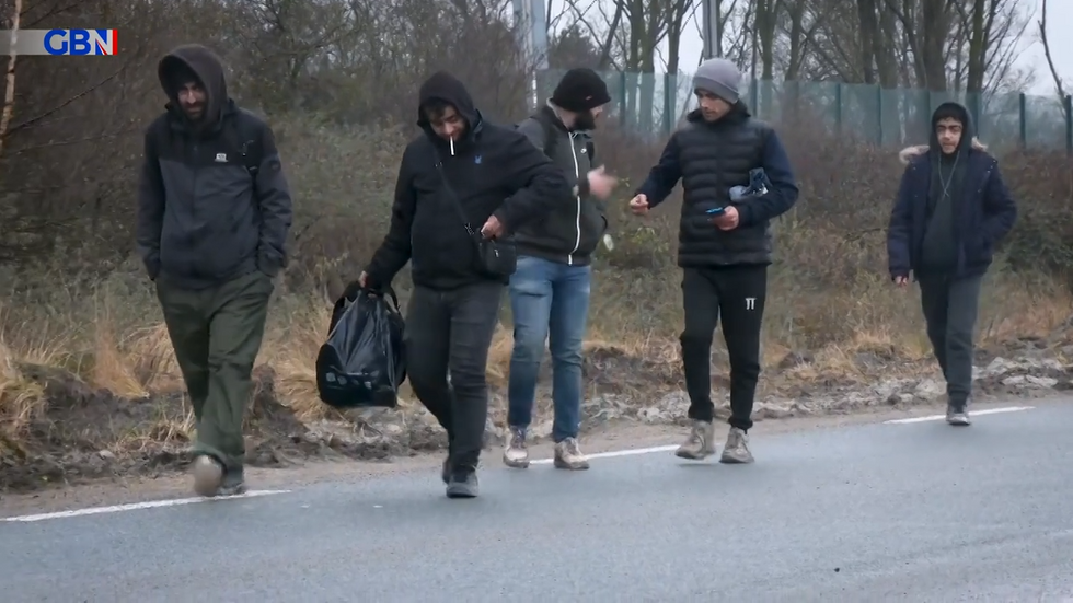 Migrants walk down road in France