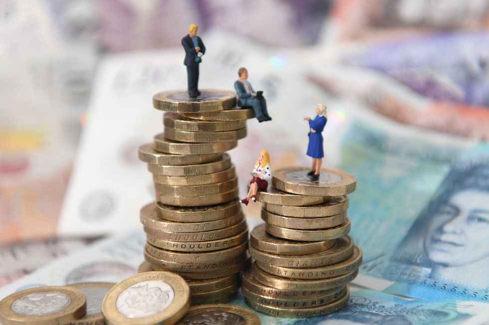 Models of men and women on a pile of coins and bank notes