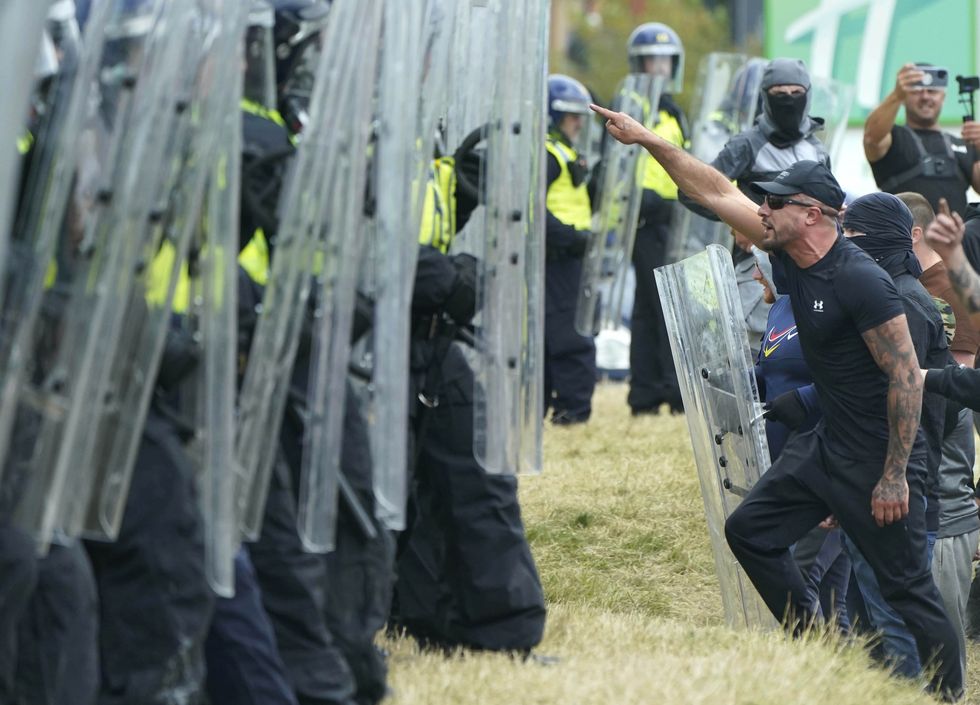 Morgan Hardy (right) facing police officers as trouble flared during an anti-immigration demonstration outside the Holiday Inn Express in Rotherham, South Yorkshire