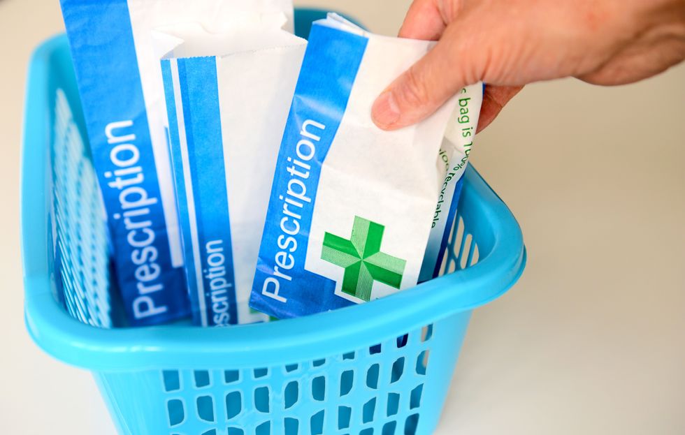 NHS prescription packet in basket at pharmacist