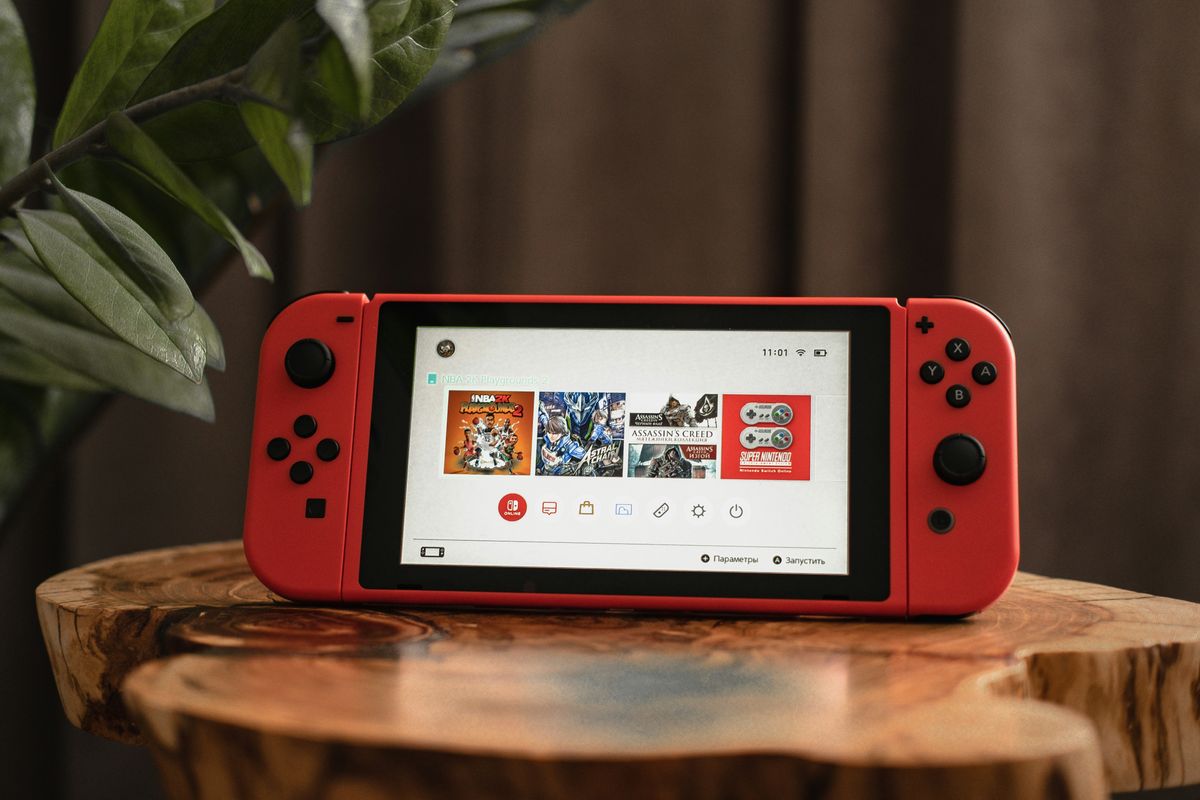 nintendo switch in red pictured on a wooden stump in a living room 