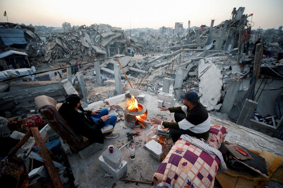 Palestinians sit next to a fire among the rubble of buildings destroyed during the Israeli offensive\u200b