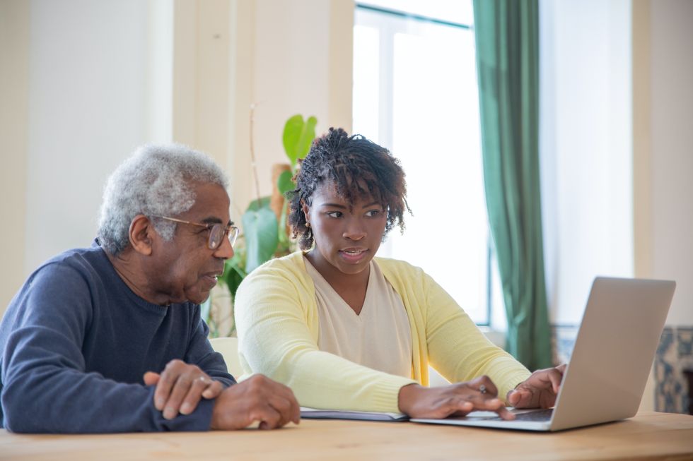 Pensioner and younger woman look at laptop