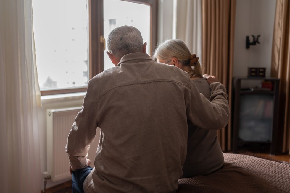 Pensioner couple sit on bed