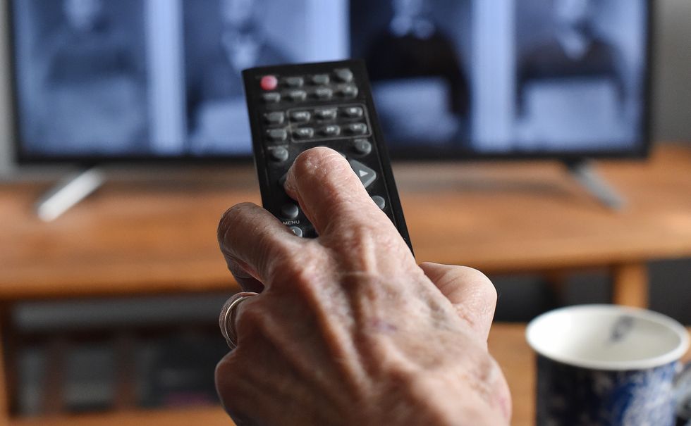 Pensioner holding TV remote