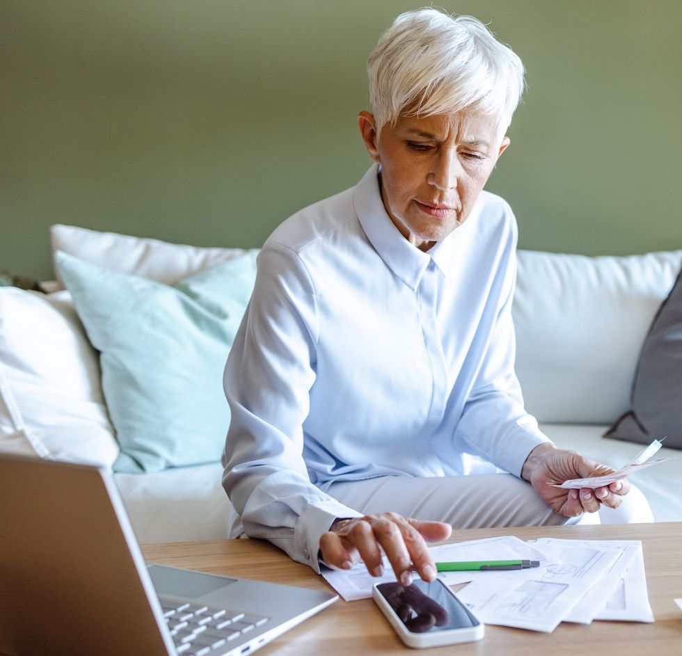 Pensioner looks at phone while sorting finances