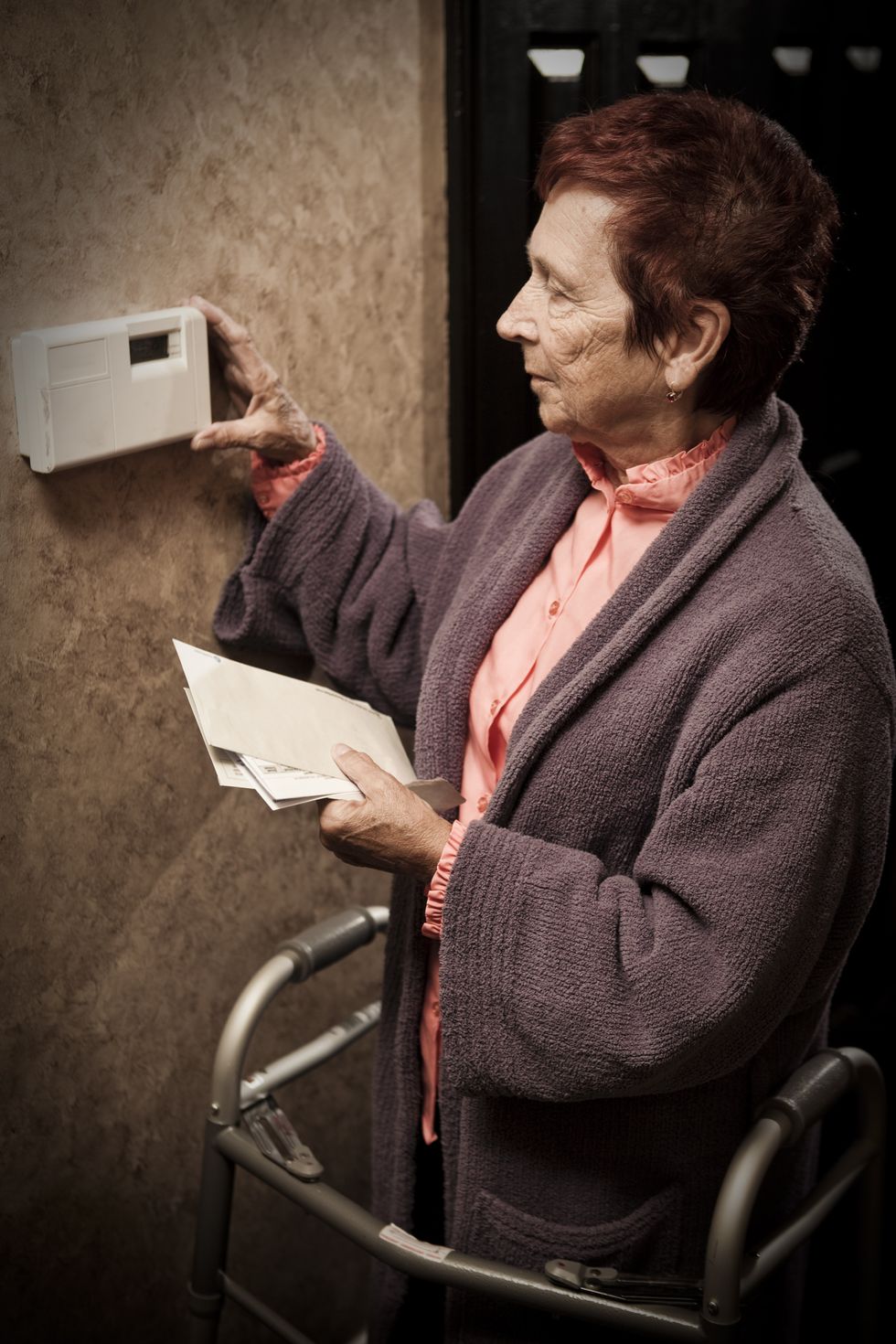 Pensioner with energy bills looks at thermostat