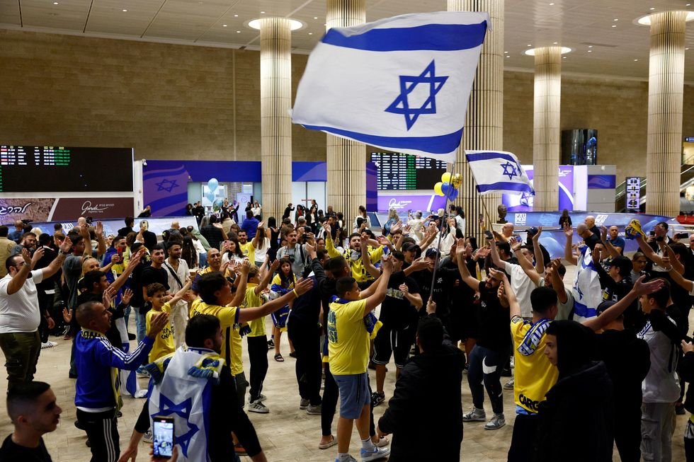 People celebrate as Maccabi Tel Aviv soccer fans arrive at the Ben Gurion International Airport, after overnight attacks after the match between Maccabi and Ajax Amsterdam