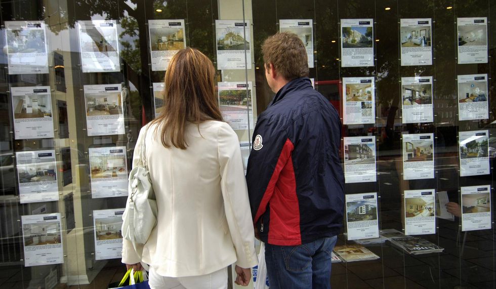 People looking at properties for sale in estate agent window