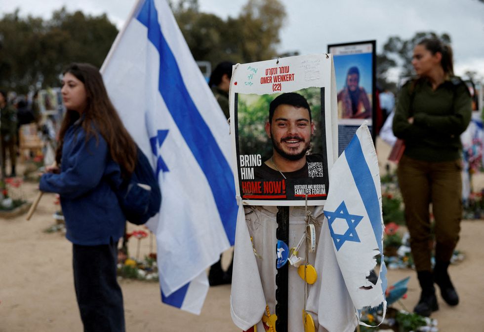 People walk near a poster depicting a hostage Omer Wenkert, at the site of the Nova festival where party goers were killed and kidnappedu200b