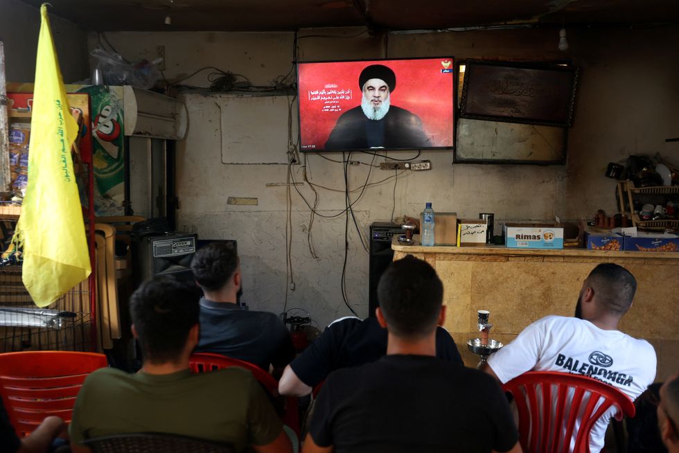 People watch Lebanon's Hezbollah leader Sayyed Hassan Nasrallah delivering a televised address