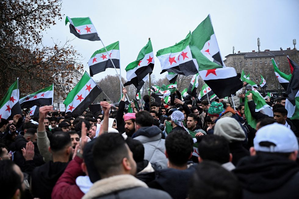 People wave Syrian opposition flags, as they gather at Oranienplatz square, after Syrian rebels announced that they have ousted Syria's Bashar al-Assad, in Berlin, Germany