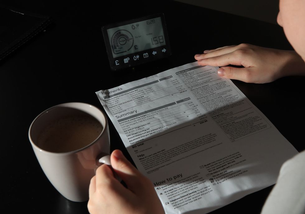 Person looks at energy bills beside a mug of coffee