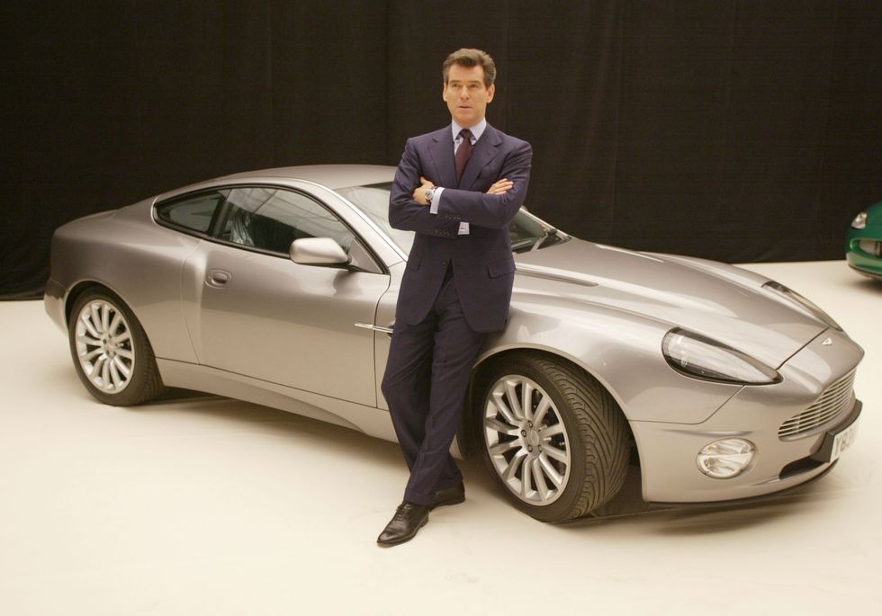 Pierce Brosnan poses with an Aston Martin V12 Vanquish at a press conference for Die Another Day