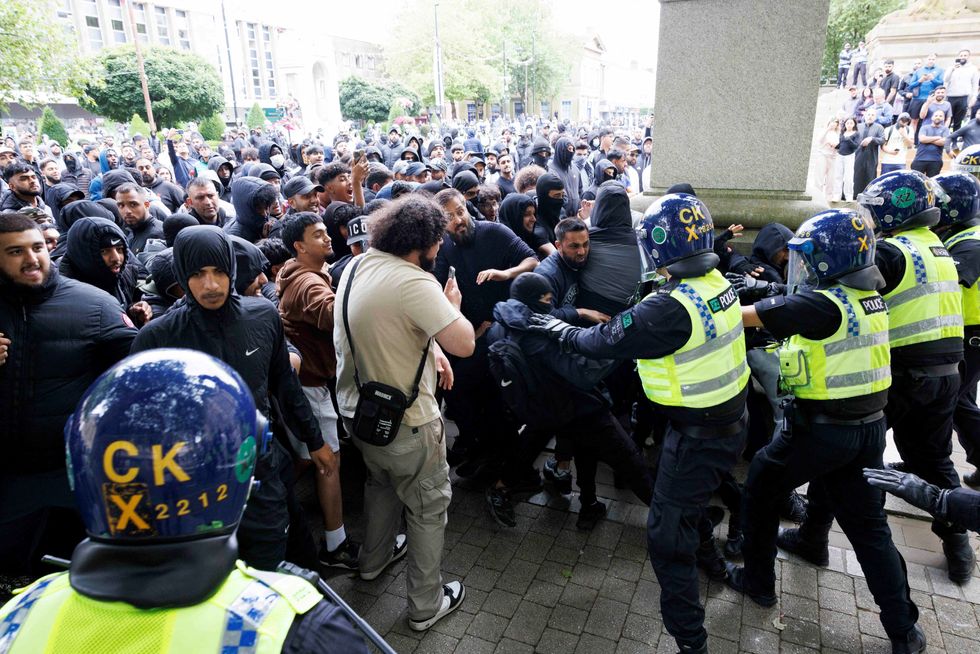 Police officers stand guard as counter-protesters push against the police