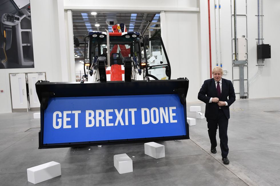 Prime Minister Boris Johnson walks away after driving a Union flag-themed JCB, with the words "Get Brexit Done" inside the digger bucket,