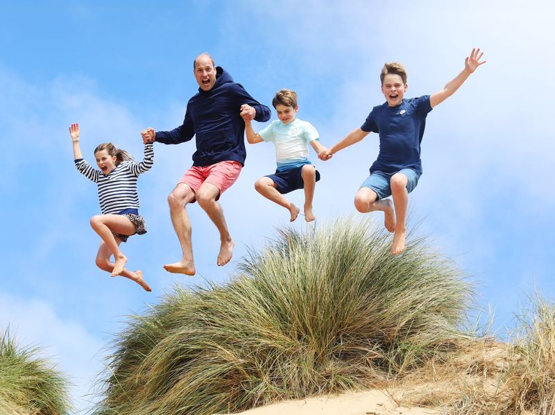 Prince William and his three children jumping at the beach in Norfolk