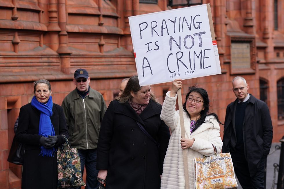 Protester holding sign over abortion clinic prayers