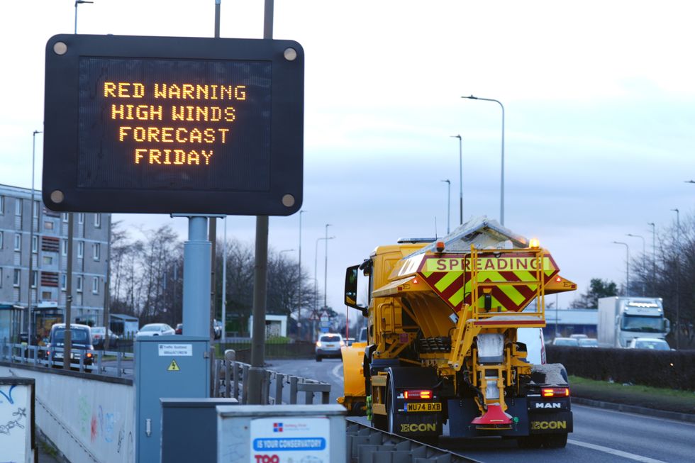 Red weather warning sign next to a busy road