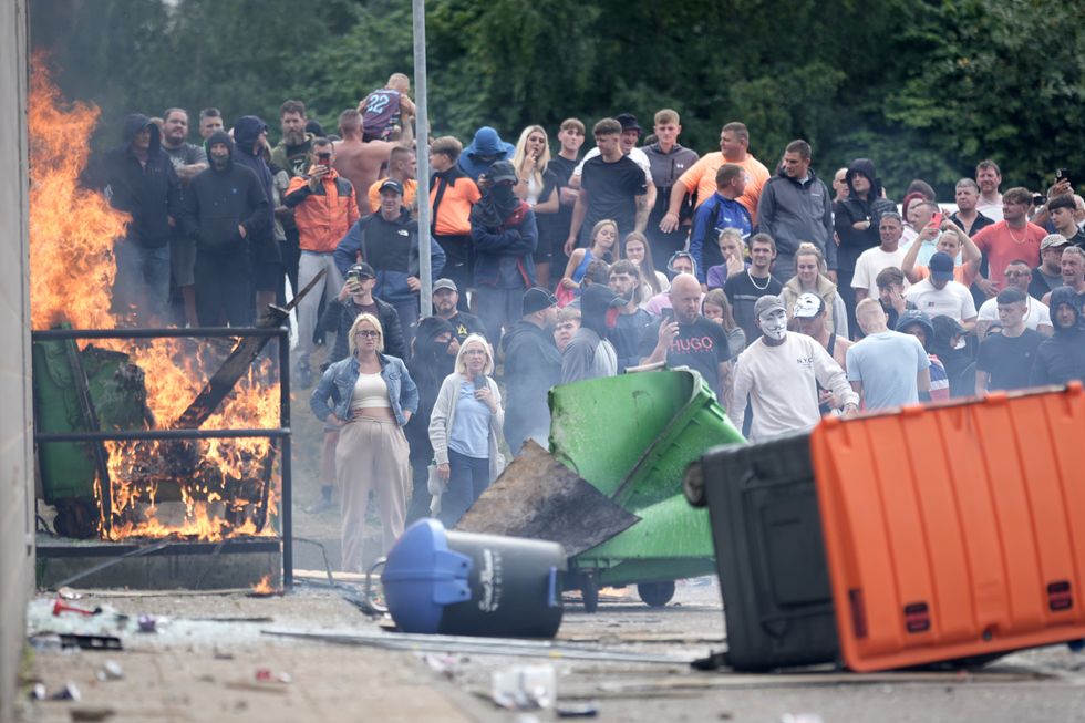 Rioters outside of a burning hotel