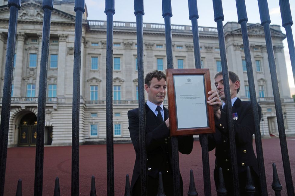 Royal household staff posts a notice on the gates of the Buckingham Palace