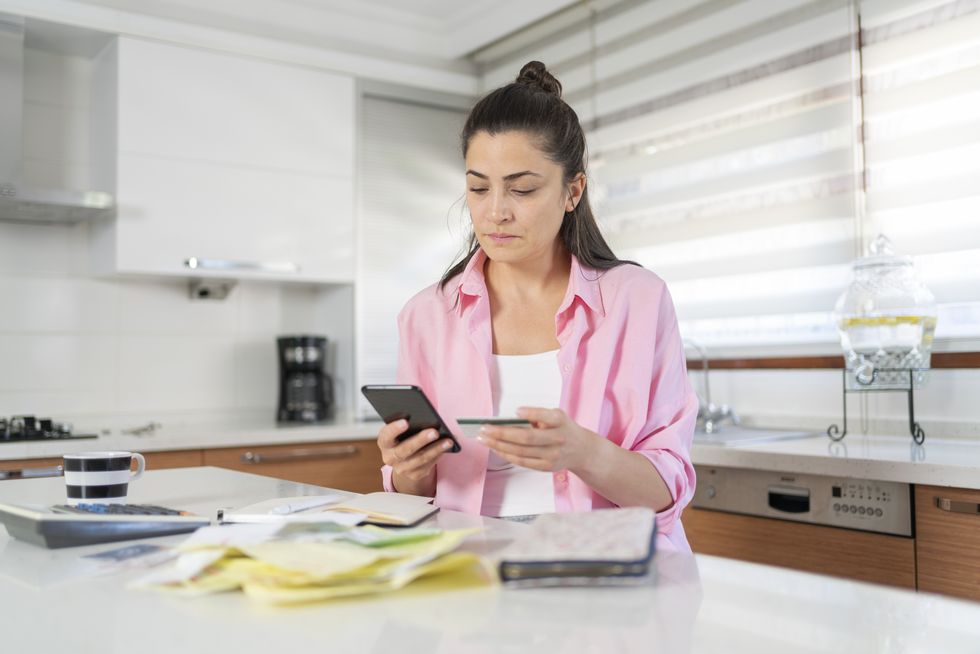 Saver looks at mobile with bank card in other hand