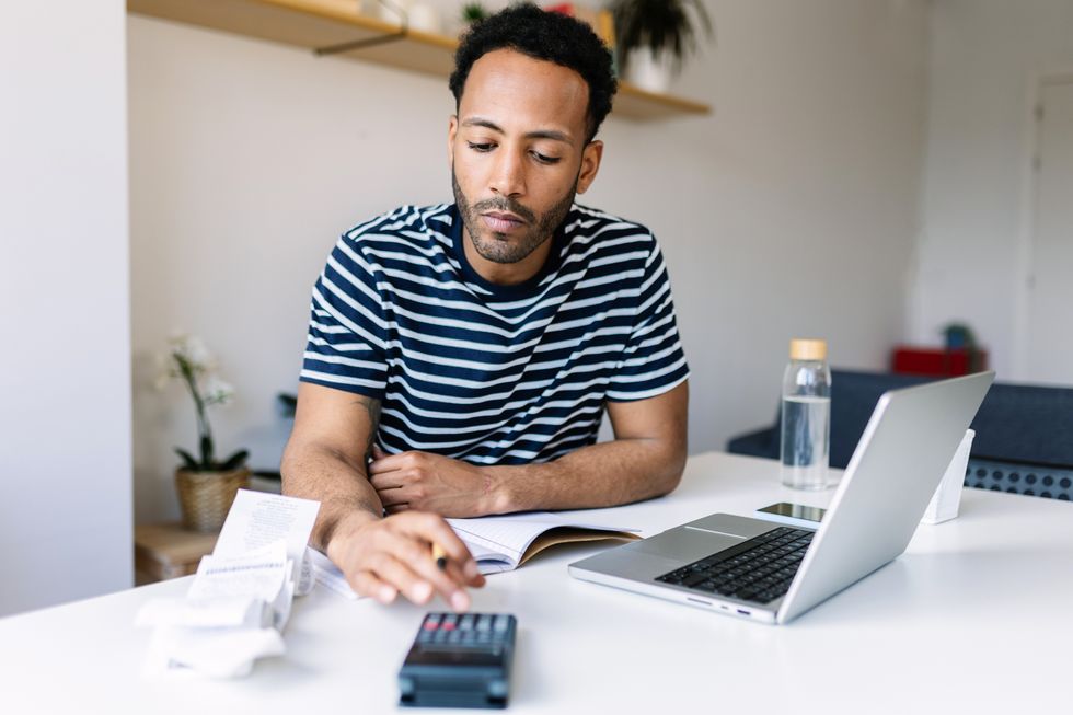 Saver looks at receipts and calculator beside notepad and laptop