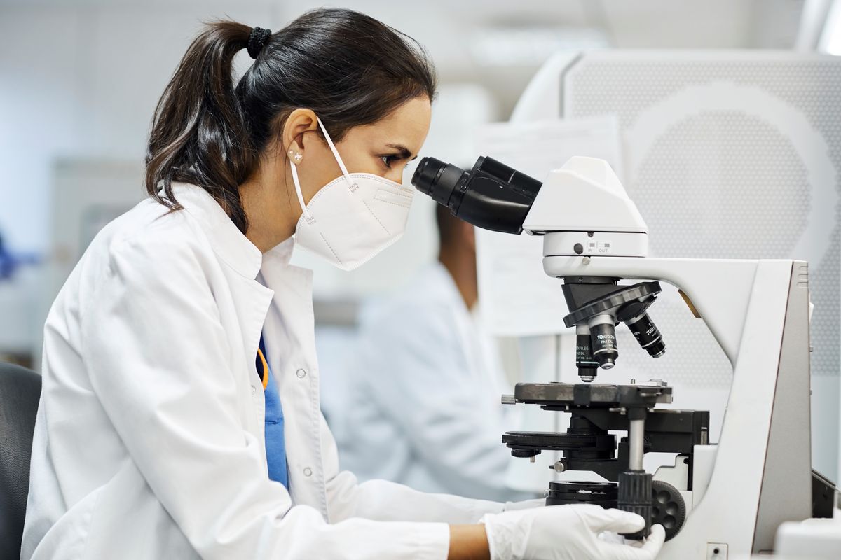 Side view of female doctor using microscope during research in laboratory