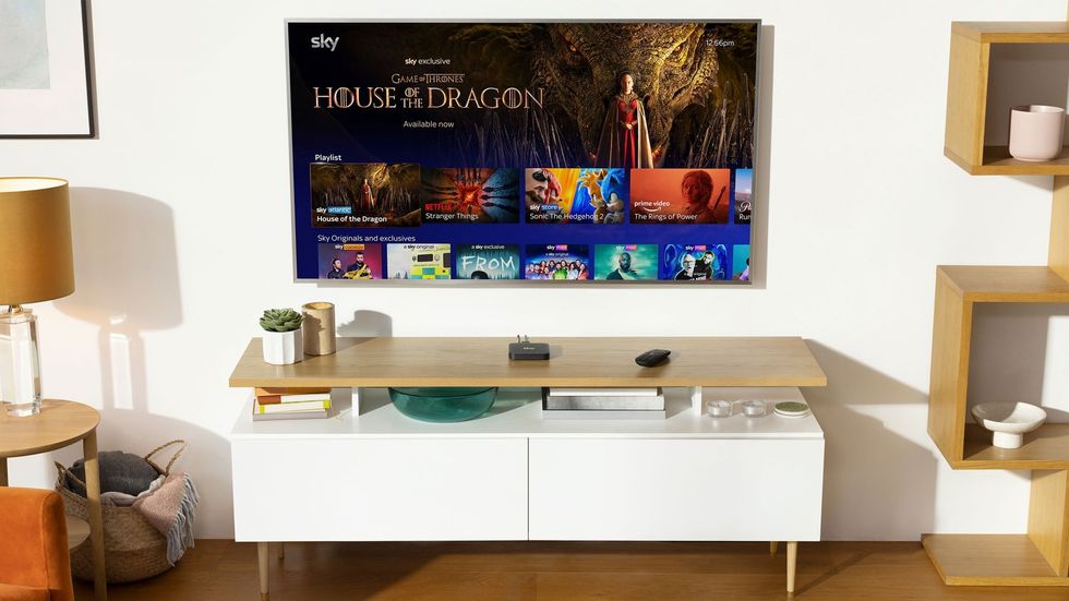 sky stream box pictured on a media unit with the flatscreen showing sky tv content on-screen