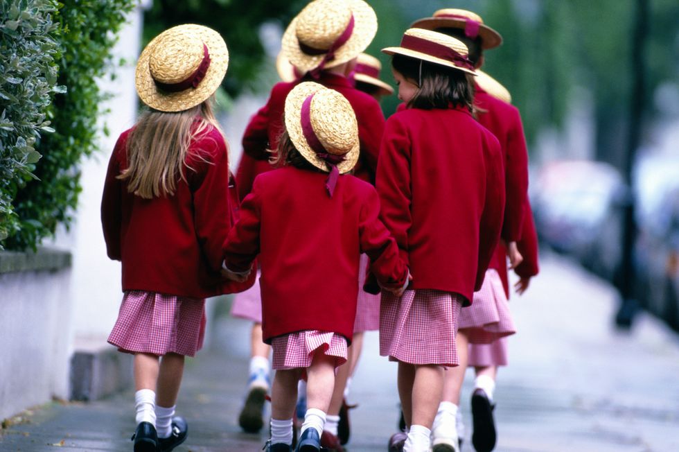 Stock image of children walking to school in red school uniform